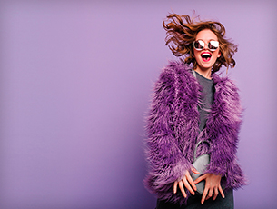 Laughing Women In Purple Fur Jacket Complimenting Purple Wall