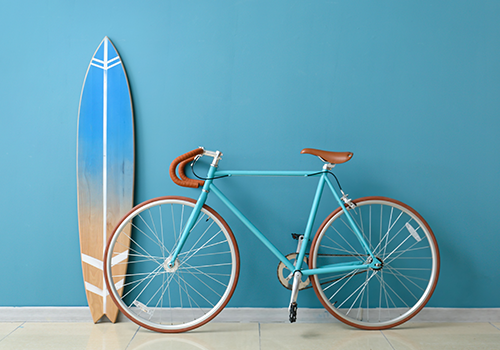 Blue Surfboard And A Cycle In Front Of Blue Wall